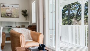 A living room with a sofa, a coffee table with a tray, a bookshelf, and a painting of sheep.