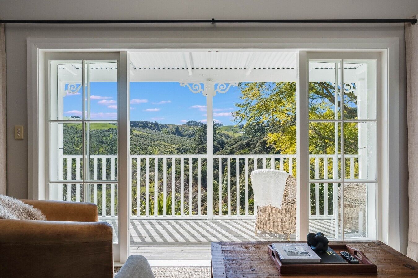 A room with a view of a green landscape through large windows.