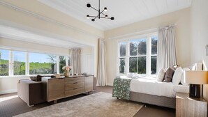 A bedroom with a bed, a dresser, a nightstand, and a window with curtains.