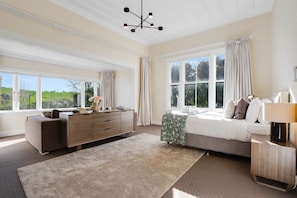 A bedroom with a bed, a dresser, a nightstand, and a window with curtains.