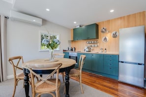 A modern kitchen with teal cabinets, a stainless steel refrigerator, and a dining area with a round table and chairs.