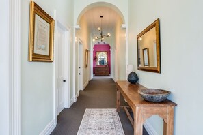 A hallway with a wooden bench, a rug, and framed certificates on the walls.