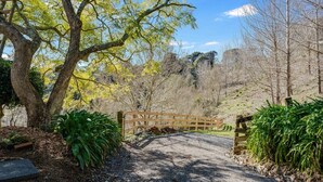 A gravel path leading to a wooden gate in a wooded area with trees and shrubs.