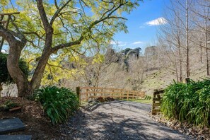 A gravel path leading to a wooden gate in a wooded area with trees and shrubs.