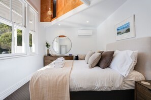 Un dormitorio con cama, mesitas de noche, un espejo y una ventana.