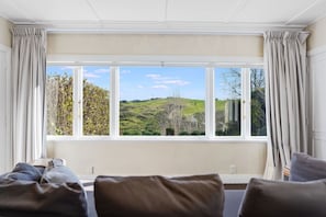 A room with a large window, a sofa, and curtains.