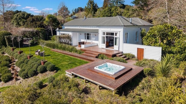A modern house with a large deck, a hot tub, and a well-maintained garden.