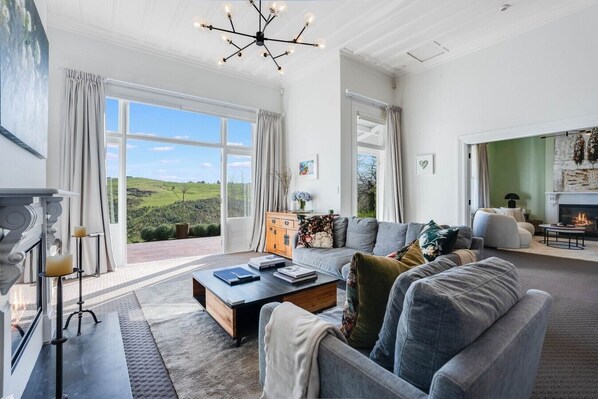 A spacious living room with a fireplace, a large sofa set, and a view of the outdoors.