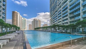 Una piscina con solárium empedrado, rodeada de edificios residenciales altos.