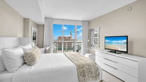 Habitación de hotel moderna con una cama grande, televisión y vistas a una obra en construcción.