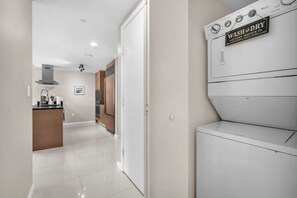 A modern kitchen with a built-in washing machine and a sign indicating 'WASH and DRY' service. - The Enso Suite Luxury Brickell (Miami)