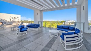 A rooftop terrace with a modern design, featuring a white pergola, a blue sofa set, and a small round table. - New Modern 2BR/2BA Design District + Free Parking (Miami)
