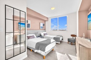 A modern hotel room with two beds, a desk, and a large window with a city view. - New Modern 2BR/2BA Design District + Free Parking (Miami)