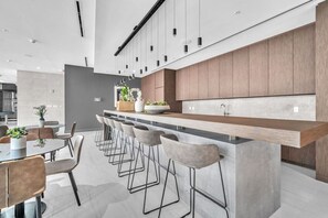 A modern kitchen with a bar area, bar stools, and a dining table with chairs. - New Modern 2BR/2BA Design District + Free Parking (Miami)