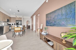 A modern kitchen with a dining area, a large painting on the wall, and a plant on the side. - New Modern 2BR/2BA Design District + Free Parking (Miami)