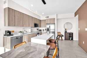 Uma cozinha moderna com uma ilha central, eletrodomésticos de aço inoxidável e um espaço de refeições com mesa de mármore.