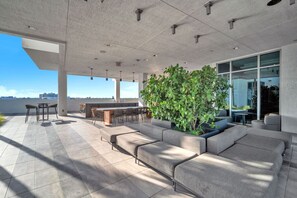 An outdoor patio with a bar area, seating, and a large planter with greenery. - New Modern 2BR/2BA Design District + Free Parking (Miami)