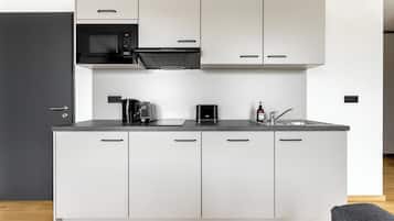 A modern kitchen with white cabinets, a black microwave, a coffee maker, and a sink.