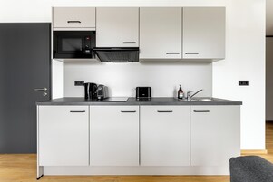 Una cocina moderna con armarios blancos, un microondas negro, una cafetera y un lavabo.