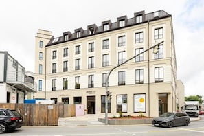 A multi-story building with a flat facade, a ground-level entrance, and a visible storefront.