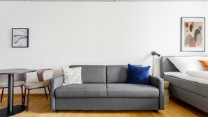 A modern living room with a grey sofa, a white couch, a round table, and two chairs.