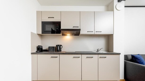 A modern kitchen with a microwave, coffee maker, and a sink.
