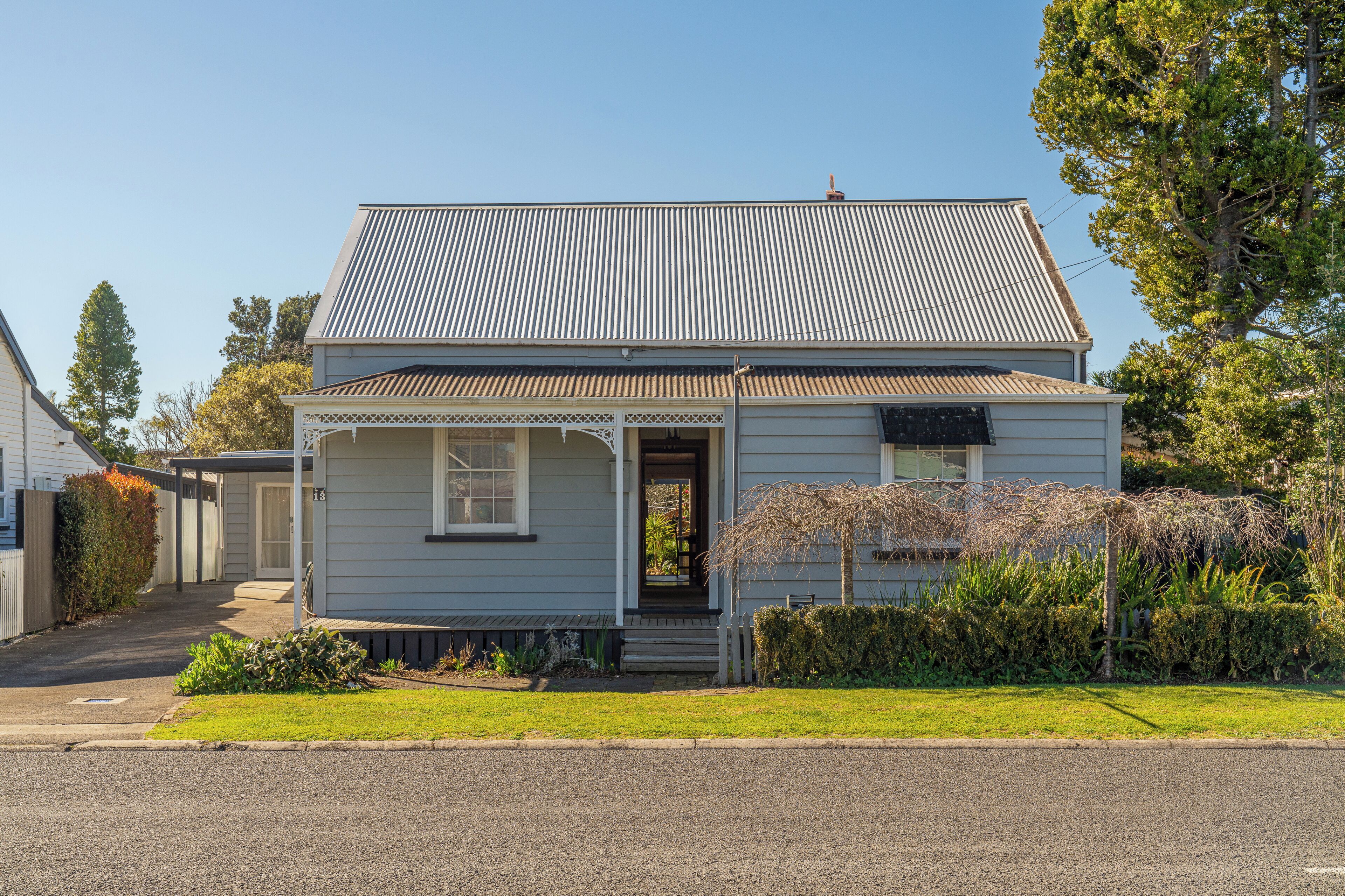 A single-story house with a gabled roof, a front porch, and a small garden area.
