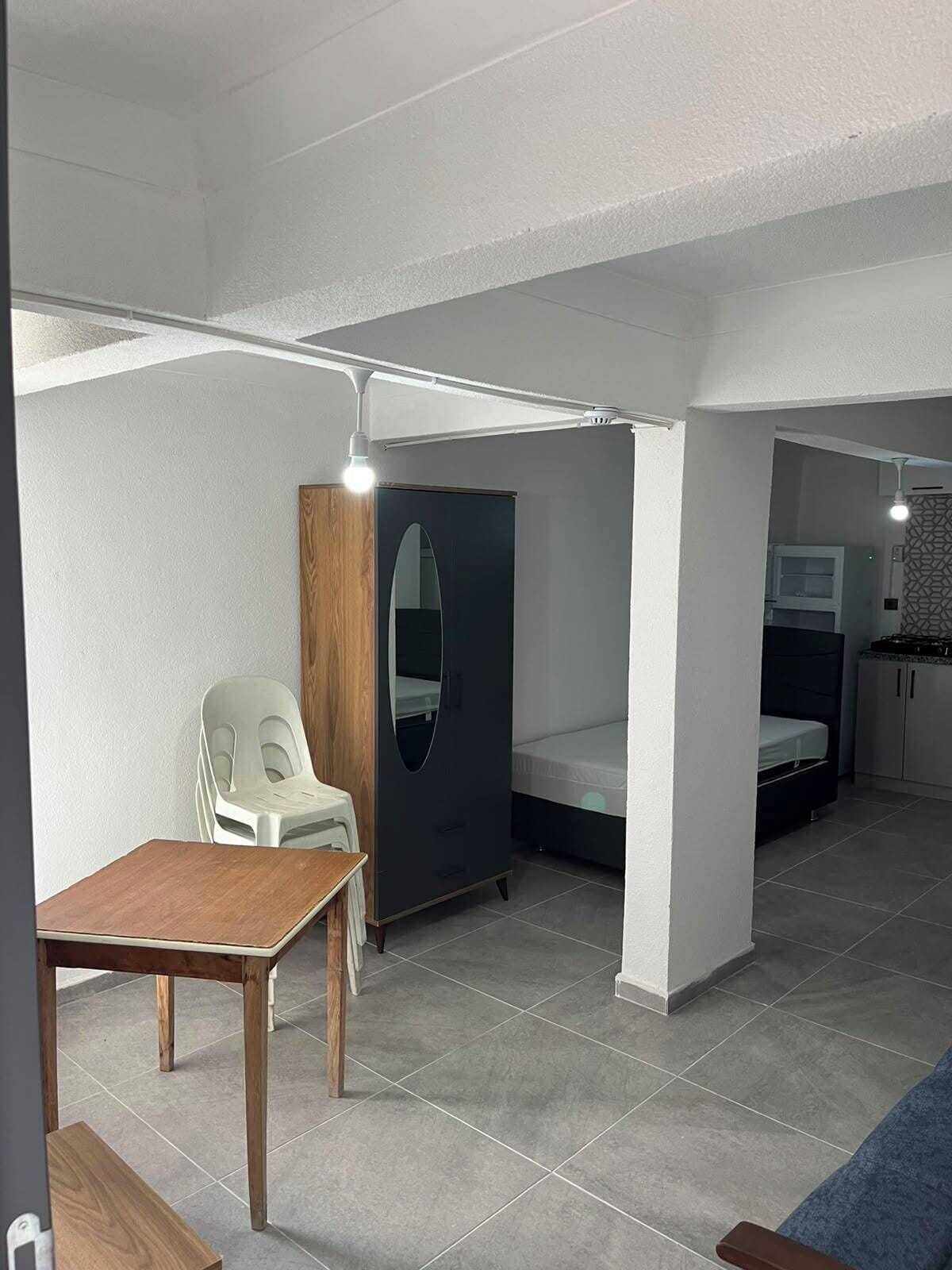 Une petite pièce comprenant un lit, un bureau, une chaise et une armoire.