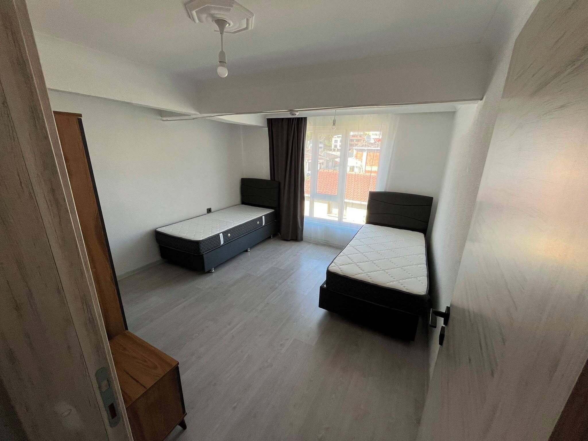 A room with two beds, a window, and a ceiling fan.