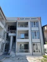 Un edificio de varios pisos con un cartel que dice 'RAIF ARDA APART'.