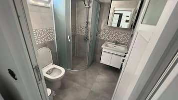 Een kleine badkamer met toilet, douchecabine en wastafel.