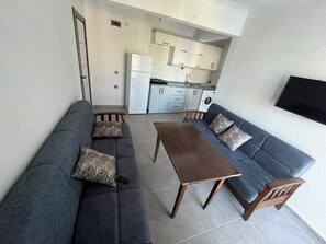 Un espacio habitable compacto con un conjunto de sofá, una mesa de comedor y un televisor montado en la pared.