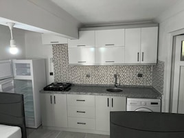 Una cocina compacta con armarios blancos, estufa integrada y lavavajillas.