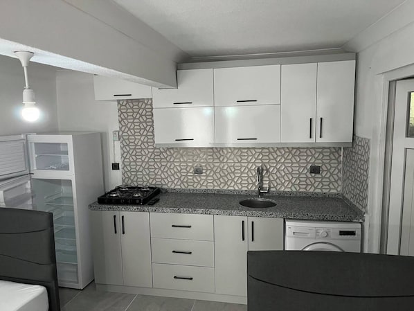 A compact kitchen with white cabinets, a built-in stove, and a dishwasher.
