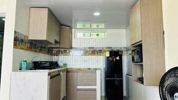A compact kitchen with a built-in stove, a refrigerator, and a microwave.