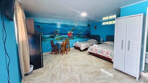 Une chambre avec une fresque murale, deux lits, un coin repas et une armoire.