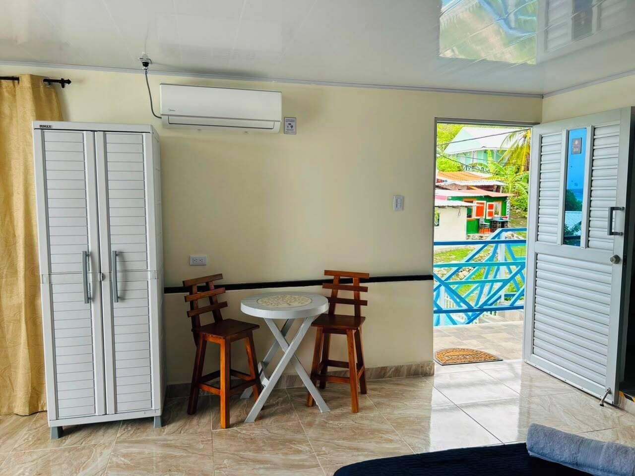 A room with a table and chairs, an air conditioning unit, and a view of the outside.