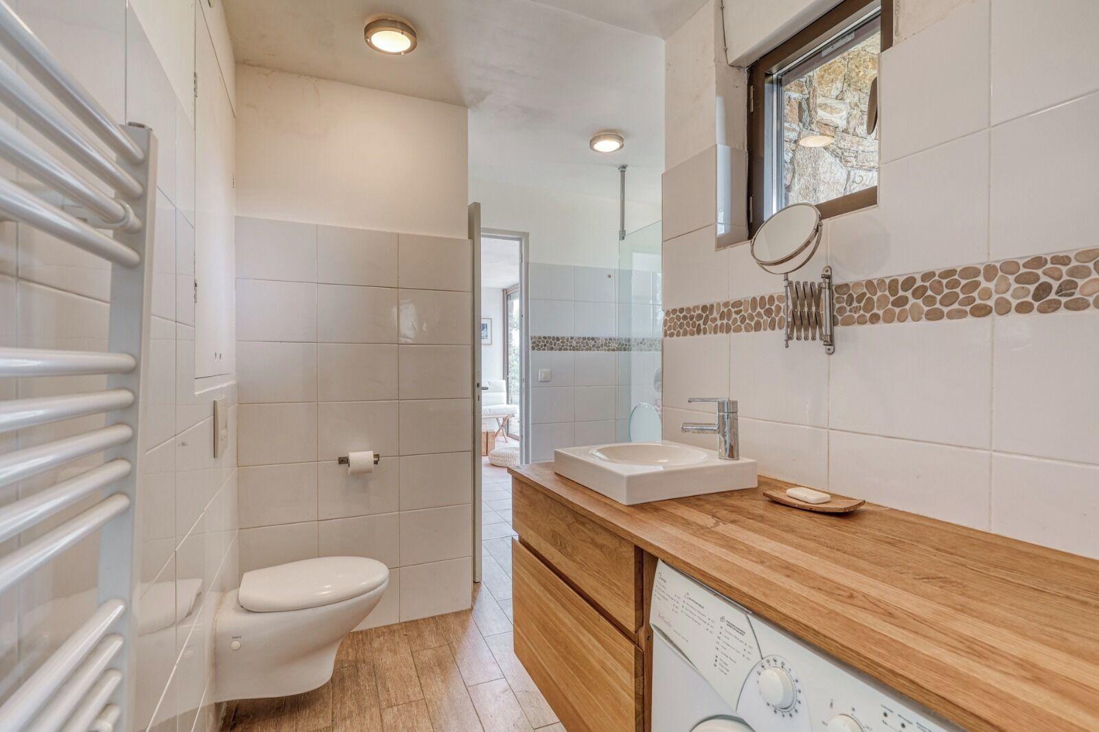 Et moderne badeværelse med toilet, håndvask og bruser.
