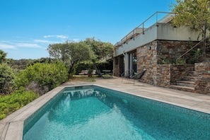 A swimming pool with a wooden deck, stone walls, and outdoor furniture. - Sea-view villa in Gaou Bénat - 4 bedrooms, air conditioning, pool, private estate (Bormes-les-Mimosas)