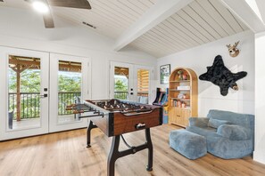 Ein Zimmer mit einem Kicker, einem Bücherregal, einer Couch und einer Meeressterne an der Wand.
