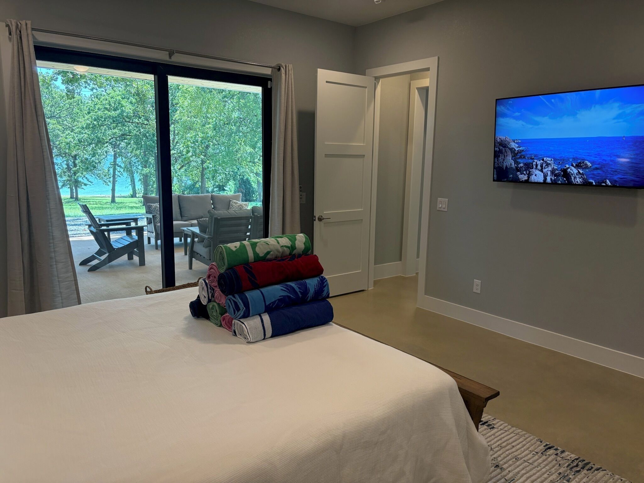 Quarto com cama, televisão na parede e vista para o exterior através de uma porta deslizante.