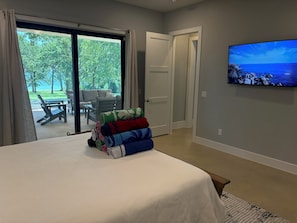 A bedroom with a bed, a TV on the wall, and a view of the outdoors through a sliding door.