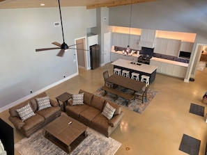 A spacious living area with a brown leather sofa, a wooden coffee table, and a ceiling fan.