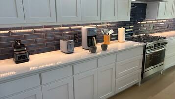 A modern kitchen with white cabinetry, a stainless steel stove, a coffee maker, and a toaster.