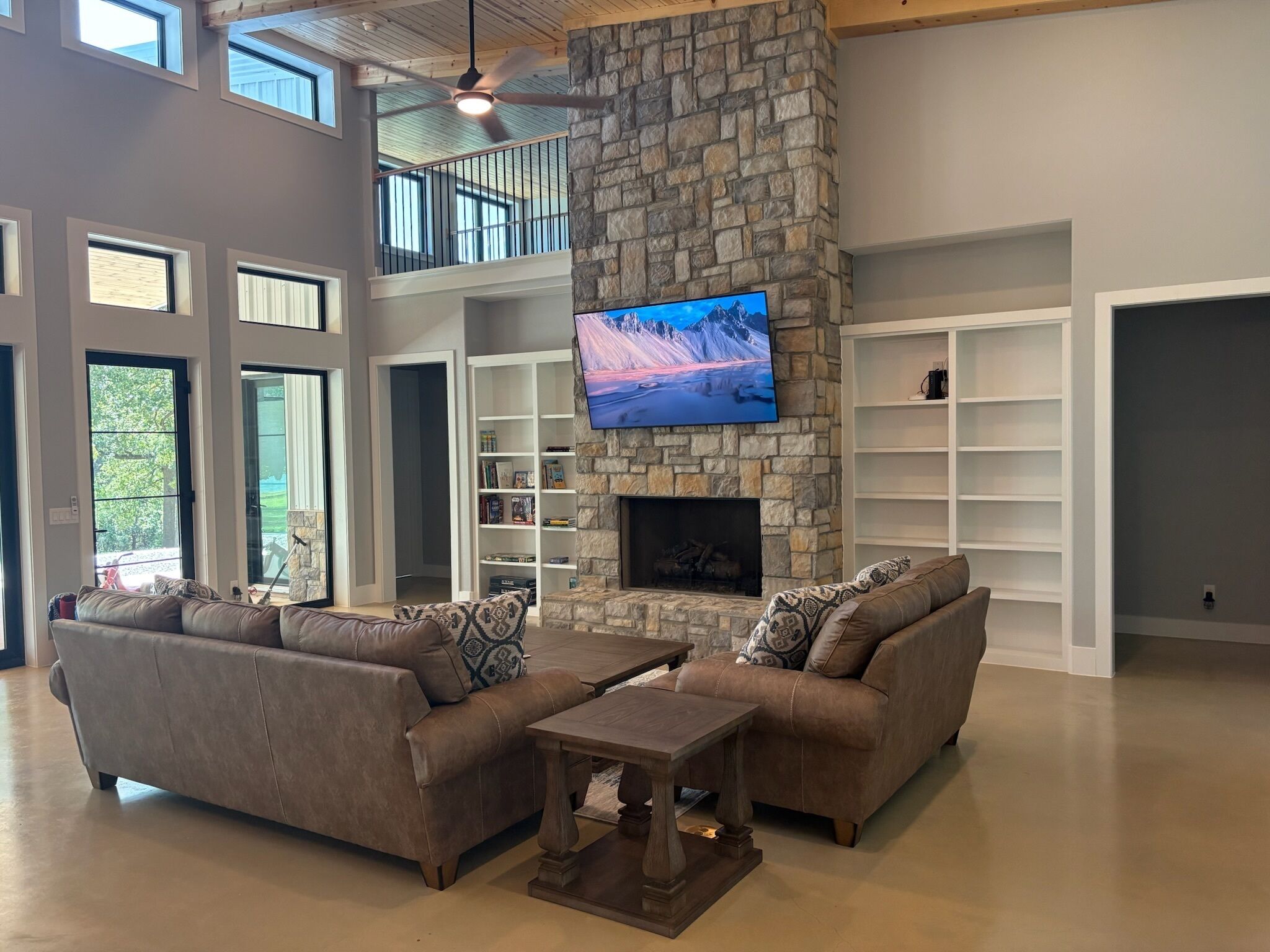 A spacious living area with a stone fireplace, a flat-screen TV, and a large sofa set.