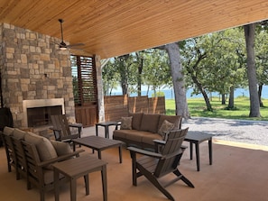 An outdoor patio with stone walls, a fireplace, and seating arrangements.