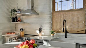 Una cocina moderna con estufa de acero inoxidable, horno integrado, campana extractora y ventana con vistas al exterior.