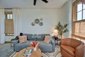 Ein Wohnzimmer mit grauem Sofa, einem braunen Ledersessel, einem Couchtisch mit Zeitschriften und einer Pflanze.