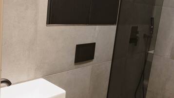A modern bathroom with a toilet, a sink, and a shower area.