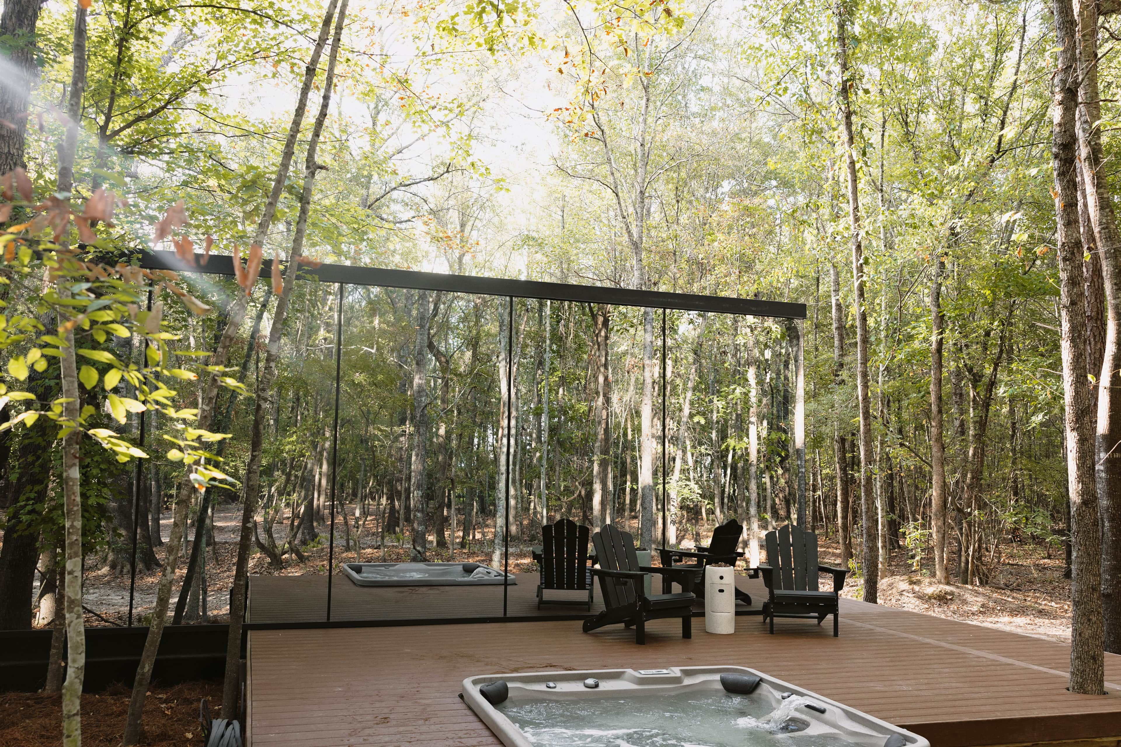 A hot tub area with seating and a glass enclosure overlooking a forest.